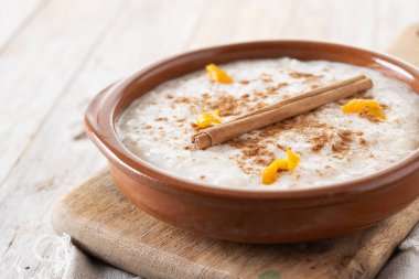 Arroz con leche. Tahta masadaki kil kasede tarçınlı sütlaç. Kapat.