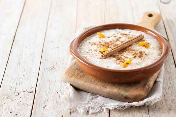 Arroz con leche. Tahta masadaki kil kasede tarçınlı sütlaç. Boşluğu kopyala