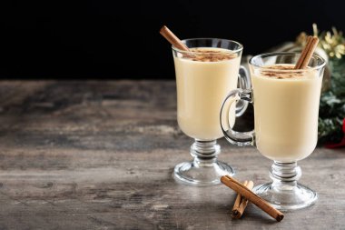 Ahşap masada tarçınlı ev yapımı eggnog. Tipik Noel tatlısı. Boşluğu kopyala