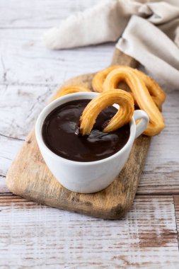 Geleneksel İspanyol churro 'ları sıcak çikolatalı kahvaltı ve ahşap masa.