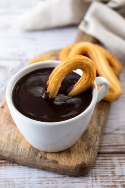 Geleneksel İspanyol churro 'ları sıcak çikolatalı kahvaltı ve ahşap masa.