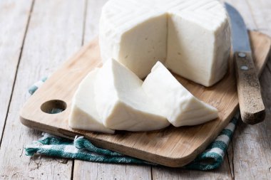 Tahta masadaki inek sütünden dilimlenmiş taze beyaz peynir.