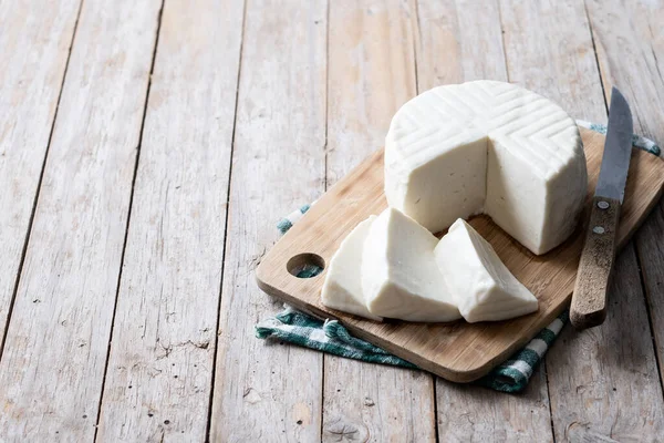 Sliced fresh white cheese from cow\'s milk on wooden table. Copy space