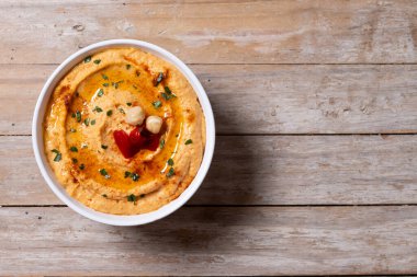 Ahşap masada kavrulmuş kırmızı biber humusu. Üst Manzara. Boşluğu kopyala