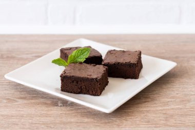 Çikolatalı brownie porsiyonu ahşap masada.