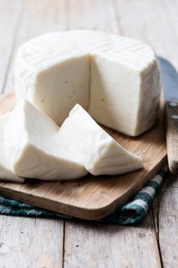 Tahta masadaki inek sütünden dilimlenmiş taze beyaz peynir.