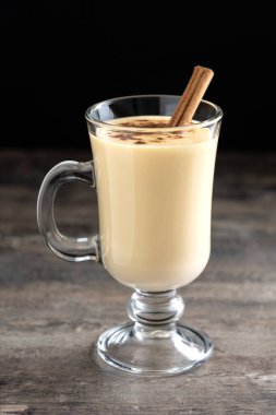 Tarçın ahşap masa üzerinde ev yapımı yumurta likörü. Tipik Noel tatlısı. 