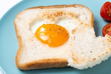 Domatesli yumurta, kalp şeklinde ekmek ve beyaz arka planda izole edilmiş tost ekmeğiyle Sevgililer Günü kahvaltısı.