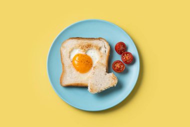 Domatesli yumurta, kalp şeklinde ve sarı arka planda tost ekmeğiyle Sevgililer Günü kahvaltısı.
