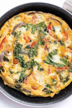 Ispanak, domates, soğan ve biberden yapılmış mermer zemin üzerinde frittata.