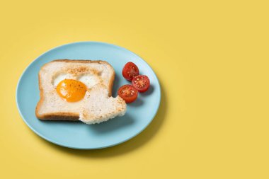 Domatesli yumurta, kalp şeklinde ve sarı arka planda tost ekmeğiyle Sevgililer Günü kahvaltısı.