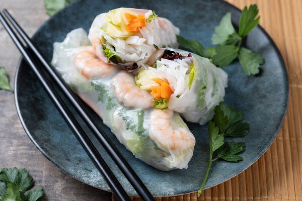Vietnamese spring rolls with vegetables, rice noodles and prawns on wooden table