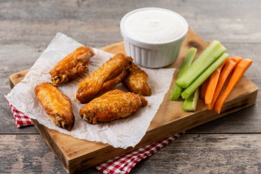 Baharatlı tavuk kanadı ve ahşap masada acı biber sosu.