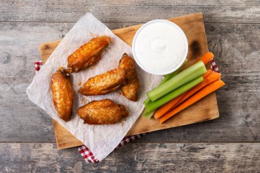 Baharatlı tavuk kanadı ve ahşap masada acı biber sosu.