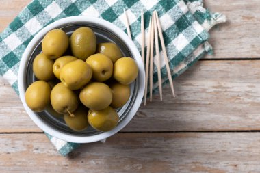 Tahta masadaki kasede yeşil zeytin.