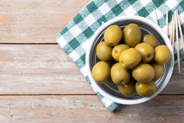 Tahta masadaki kasede yeşil zeytin.