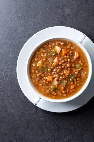 Siyah arka planda sebzeli mercimek çorbası.