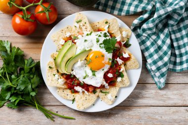 Geleneksel Meksika kahvaltısı kırmızı biberli ve ahşap masada yumurta. Üst görünüm