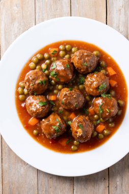 Köfte, yeşil bezelye ve ahşap masada domates soslu havuç.