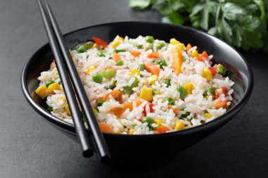 Siyah arka planda siyah kasede sebzeli beyaz pirinç.