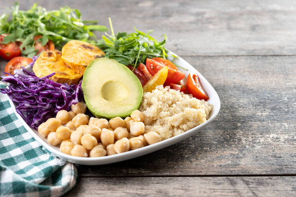 Healthy salad with avocado,lettuce,tomato and chickpeas on wooden table. Copy space