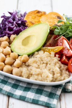 Beyaz ahşap masada avokado, marul, domates ve nohut ile sağlıklı salata. Kapat.