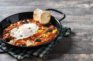 Patlıcan, yumurta, soğan, biber, ahşap masada kızartma tavasında servis edilen, domatesli sebze pisto manchego, kabak.