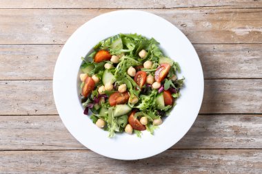 Tahta masada domates, marul ve salatalıklı sağlıklı nohut salatası.