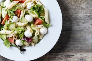 Sebzeli makarna salatası ve ahşap masada mozzarella peyniri. Üst Manzara. Boşluğu kopyala