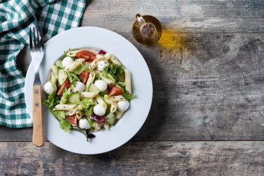 Sebzeli makarna salatası ve ahşap masada mozzarella peyniri. Üst Manzara. Boşluğu kopyala