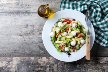 Sebzeli makarna salatası ve ahşap masada mozzarella peyniri. Üst Manzara. Boşluğu kopyala