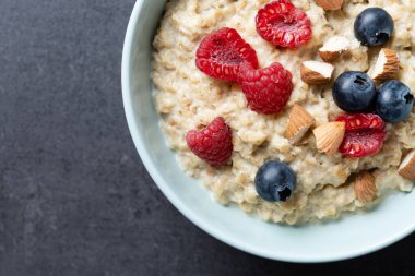Yulaf ezmeli yulaf lapası, ahududu, yaban mersini ve badem. Siyah arka planda. Üst görünüm