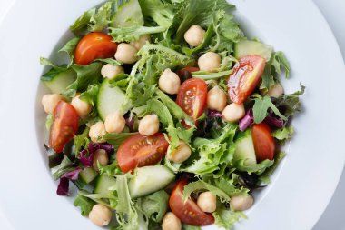 Beyaz arka planda domates, marul ve salatalıklı sağlıklı nohut salatası. Kapat.