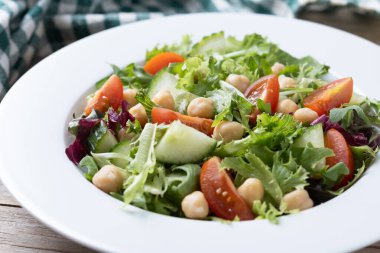 Tahta masada domates, marul ve salatalıklı sağlıklı nohut salatası.