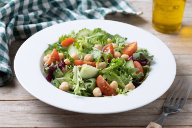 Tahta masada domates, marul ve salatalıklı sağlıklı nohut salatası.