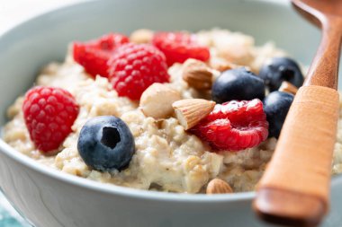 Ahududulu yulaf lapası, ahududu ve bademler ahşap masada. Kapat.