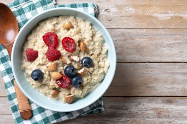 Ahududulu yulaf lapası, ahududu ve bademler ahşap masada. Üst Manzara. Boşluğu kopyala
