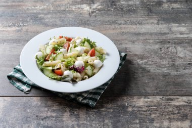 Sebzeli makarna salatası ve ahşap masada mozzarella peyniri. Boşluğu kopyala