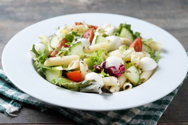 Sebzeli makarna salatası ve ahşap masada mozzarella peyniri.