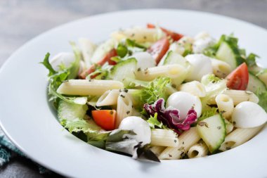 Sebzeli makarna salatası ve ahşap masada mozzarella peyniri.