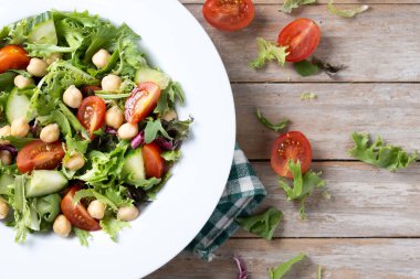 Tahta masada domates, marul ve salatalıklı sağlıklı nohut salatası.