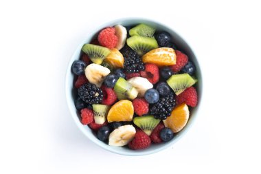 Beyaz arka planda izole edilmiş mavi bir kasede meyve salatası. Üst görünüm