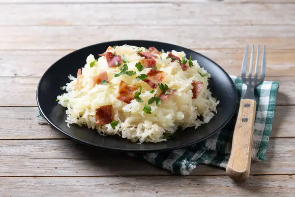 stock image Slovak potato dumplings halusky with steamed sauerkraut and bacon on wooden table