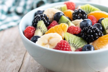 Ahşap masada mavi bir kasede meyve salatası.