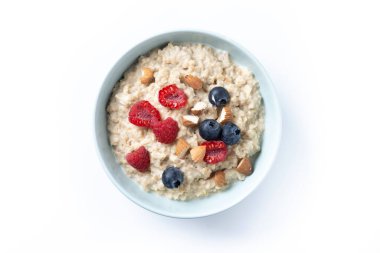 Beyaz arka planda yulaf lapası, ahududu, yaban mersini ve badem.