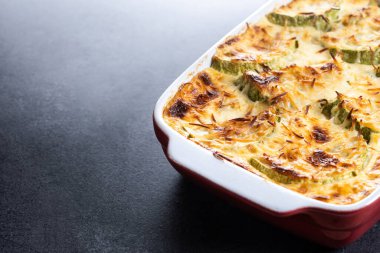 Siyah arka planda peynirli güveç ve graten kabağı. Boşluğu kopyala