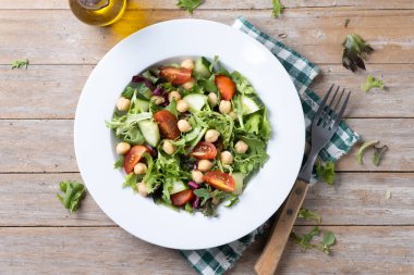 Tahta masada domates, marul ve salatalıklı sağlıklı nohut salatası.