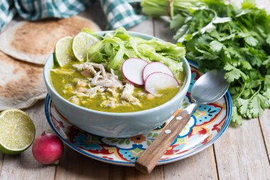 Traditional mexican green pozole soup on wooden table clipart