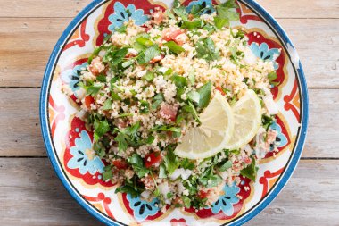 Tahta masa üzerinde kuskus olan Tabbouleh salatası. Üst görünüm