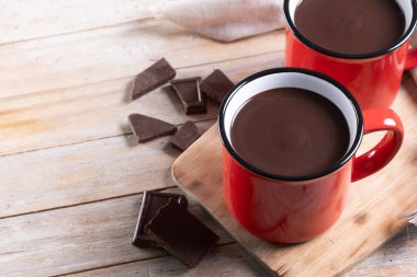 Sıcak çikolata içeceği kırmızı bardakta, tahta masada. Boşluğu kopyala